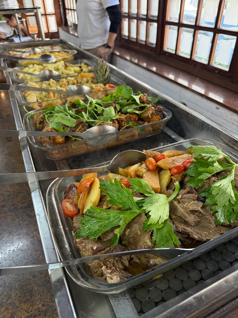 Travessas do buffet com carnes, batatas e ervas frescas